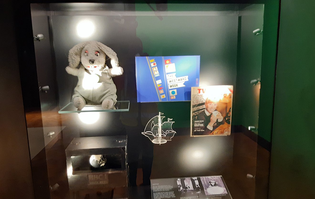 A display of objects in a case including Gus Honeybun