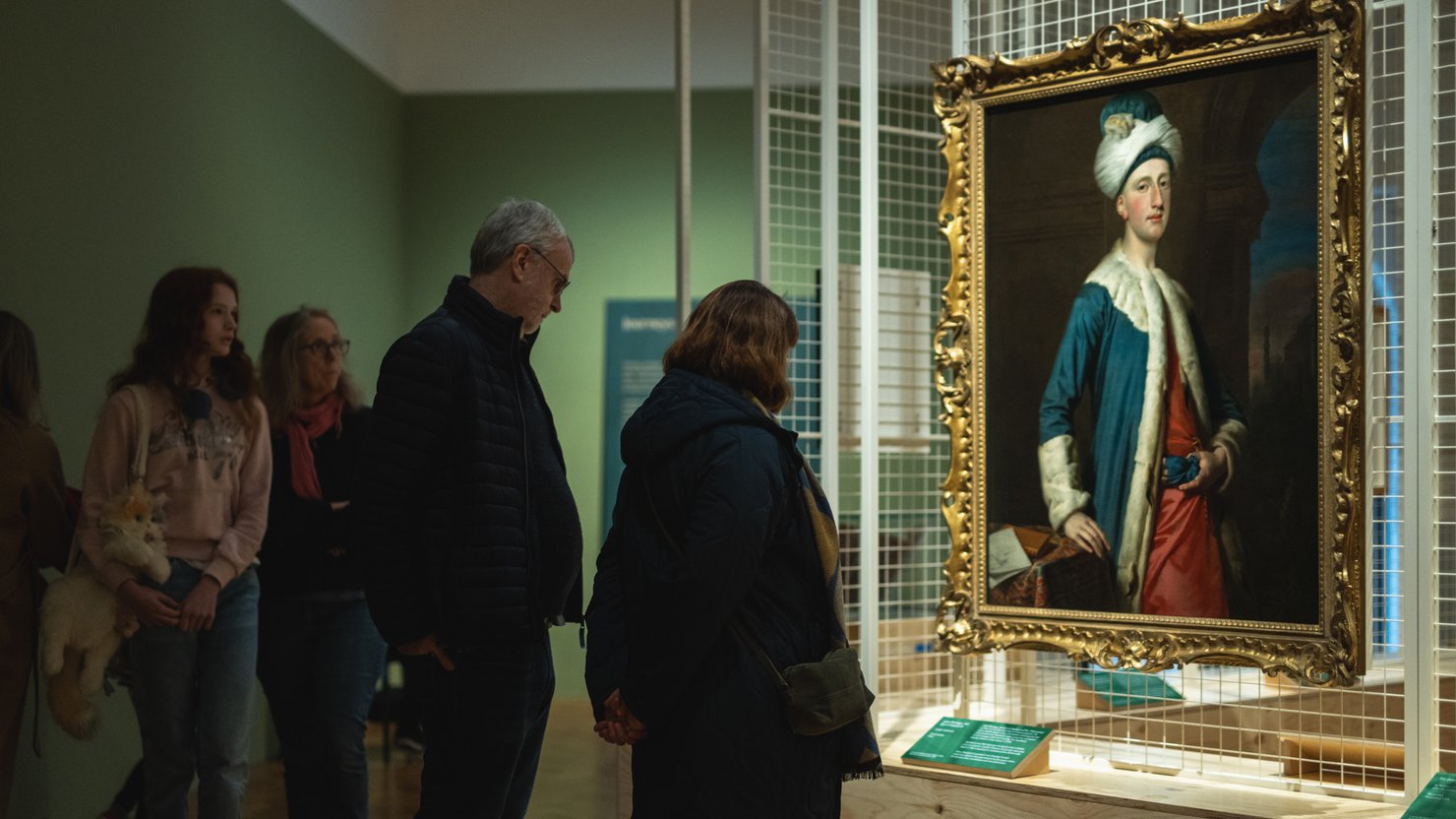Visitors looking at a painting in the Journeys with Mai exhibition at The Box Plymouth