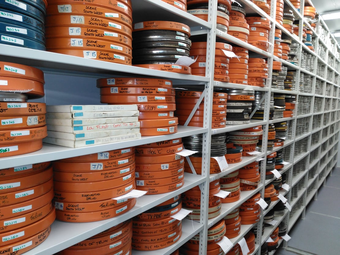 Orange film reels on a shelf in an archive store