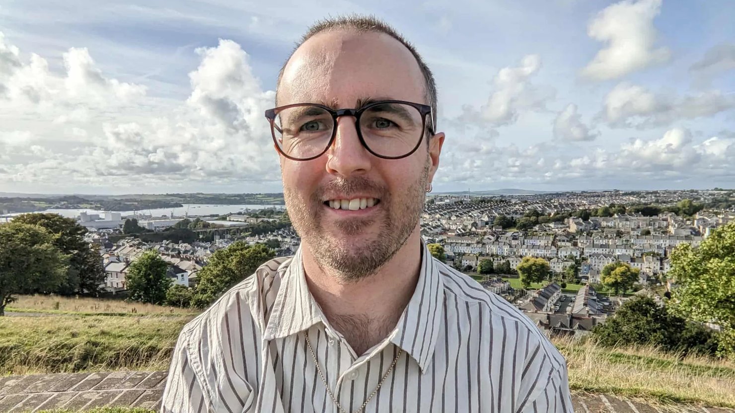 Photograph showing a man with a view of Plymouth in the background