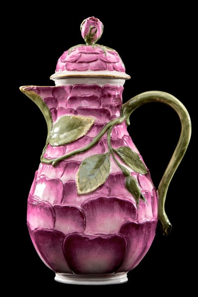 Photograph of a pink coffee pot that is decorated with a leaf and flower pattern.