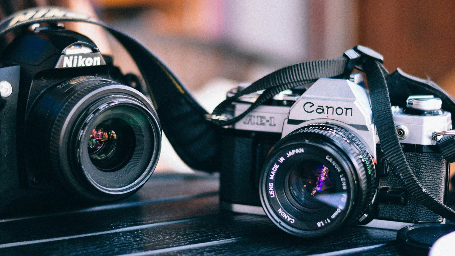 A Nikon and a Canon camera on a table