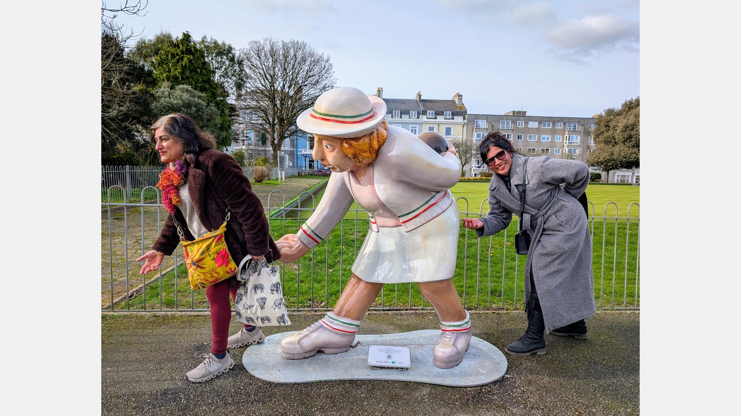 Two women with the Beryl Cook bowler sculpture