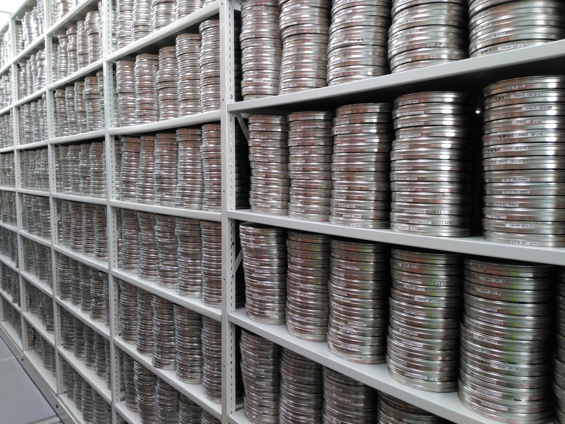 Film reels in silver cases on shelves in an archive store