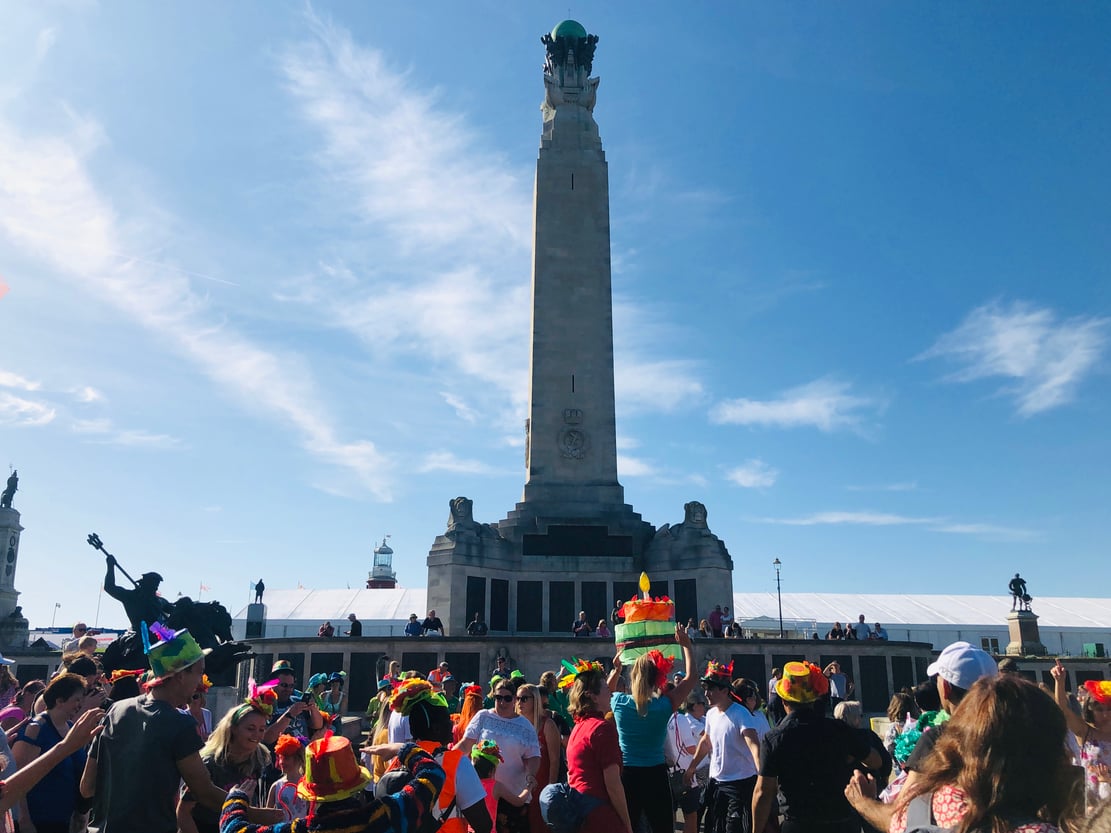 A community procession standing in front of the Royal Naval war memorial on Plymouth Hoe