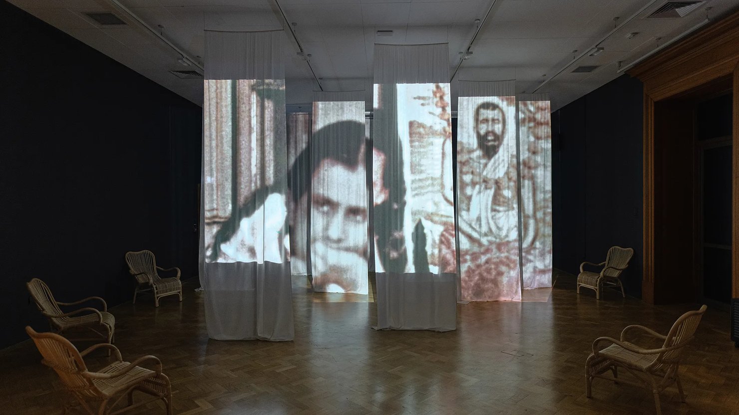 Photograph showing film projected onto drapes with seating around