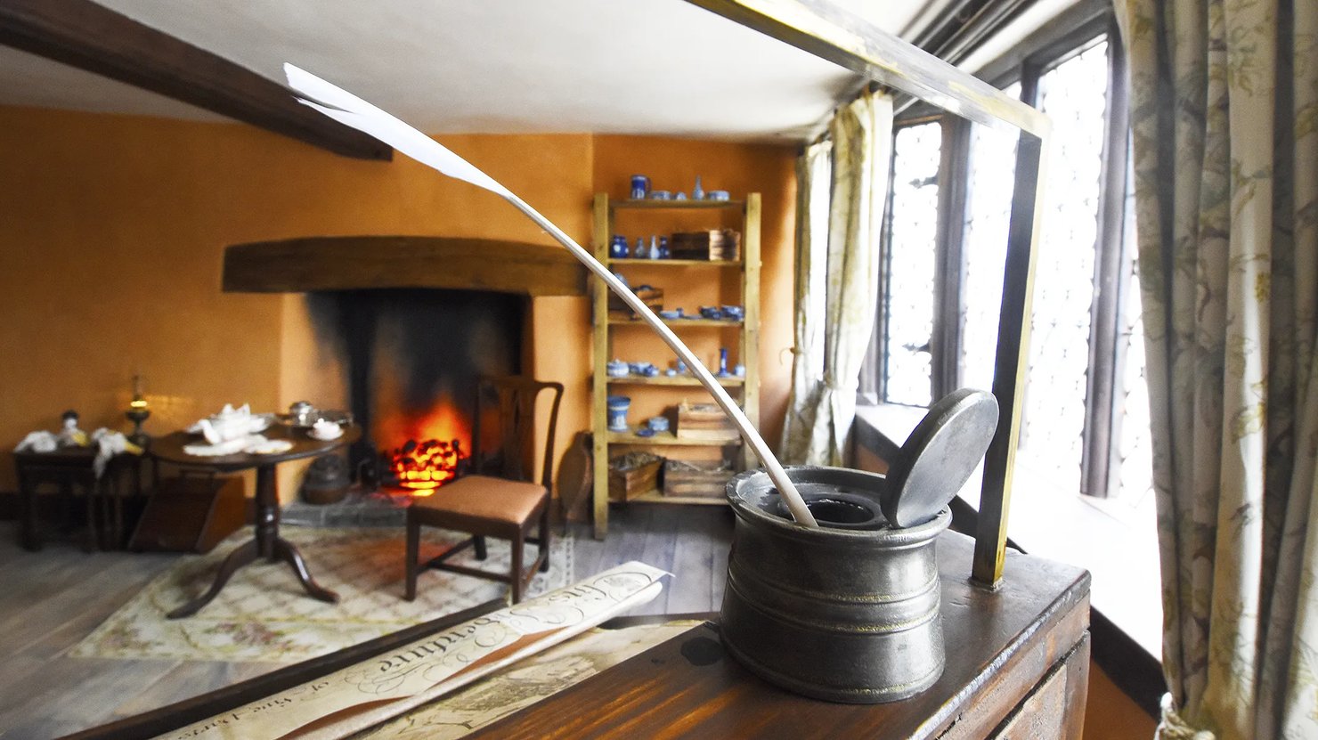 Photograph showing a dressed room in a historic house with a quill and inkwell in the foreground