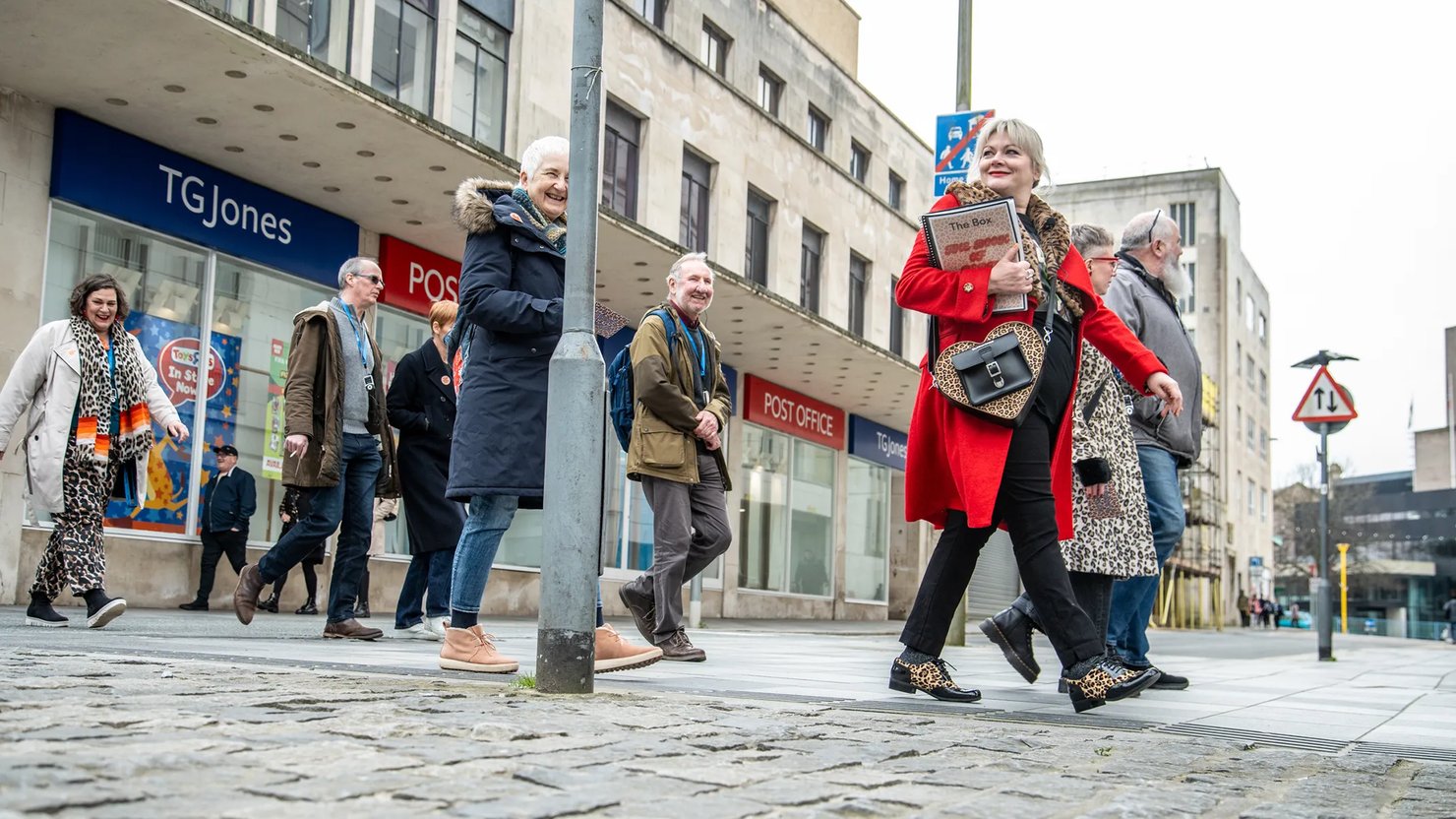 Photograph showing a group walking through a city centre with daffodils in the foreground