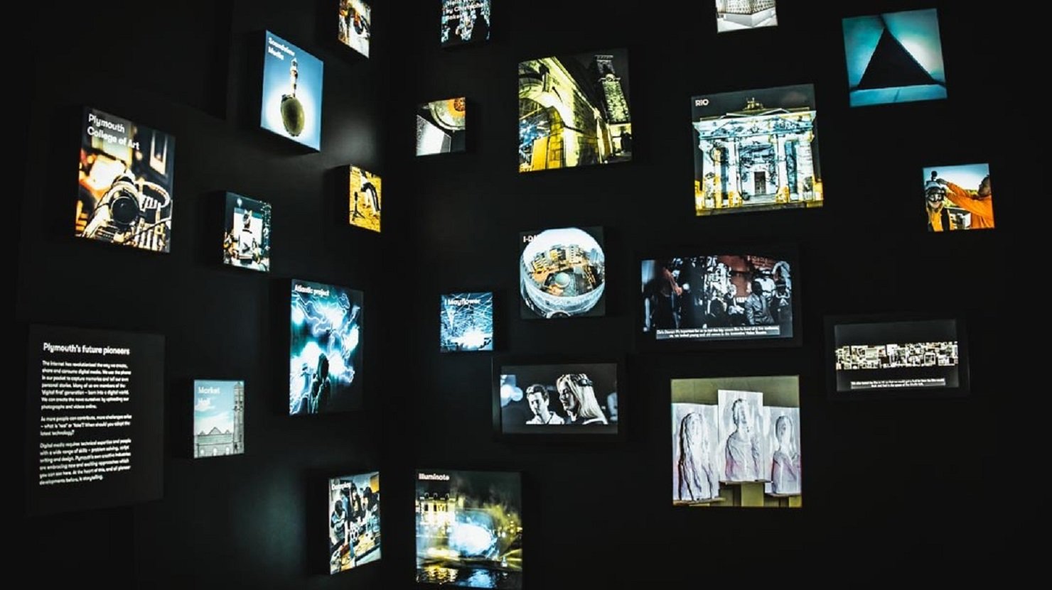 A series of different sized screens on a black wall