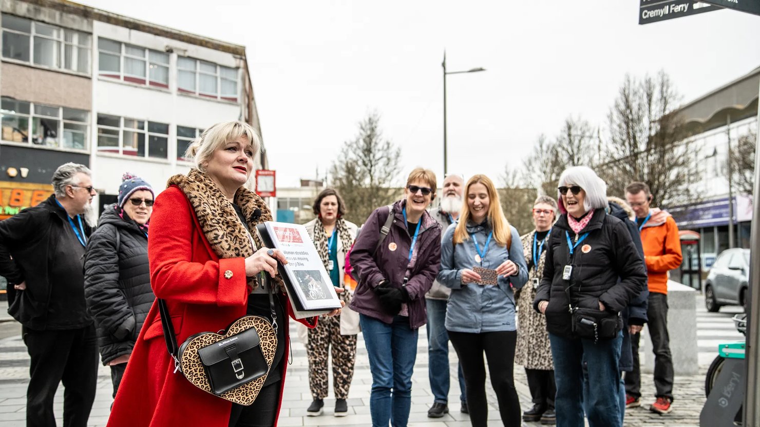 Photograph showing a group of happy people listening to a female talking in Plymouth city centre