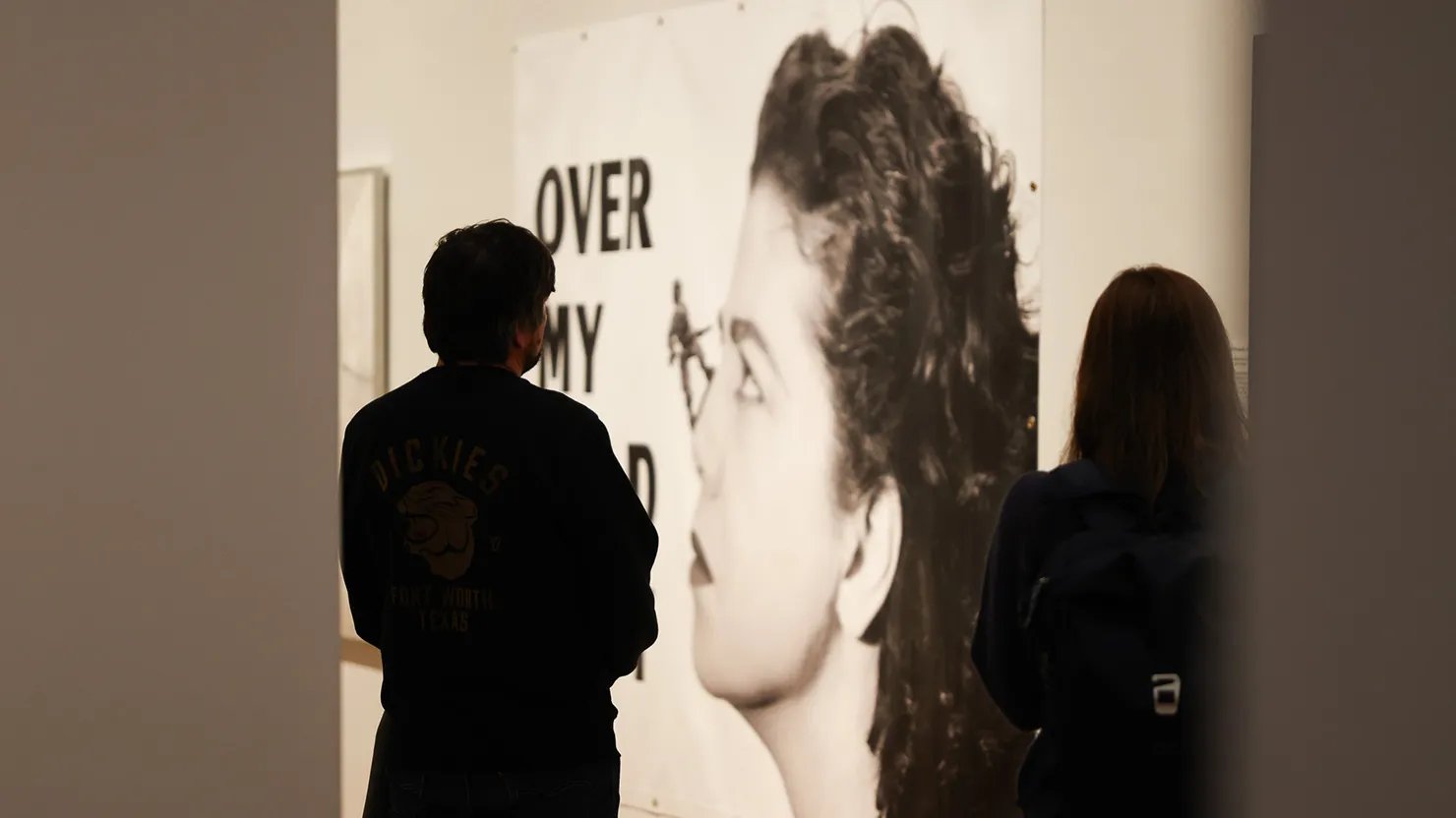 Photograph showing visitors in a gallery with a large artwork in the background