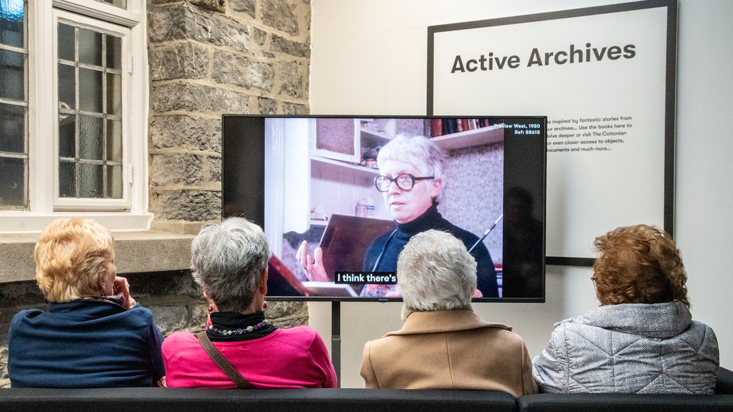 Four women watching a Beryl Cook film clip in the Active Archives gallery at The Box Plymouth