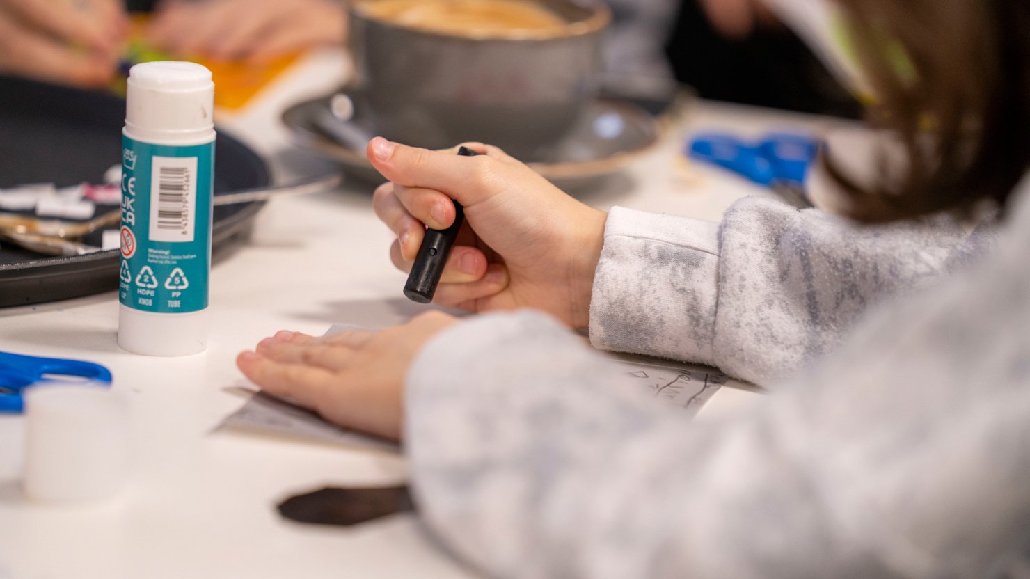 A close up of a young child holding a charcoal crayon