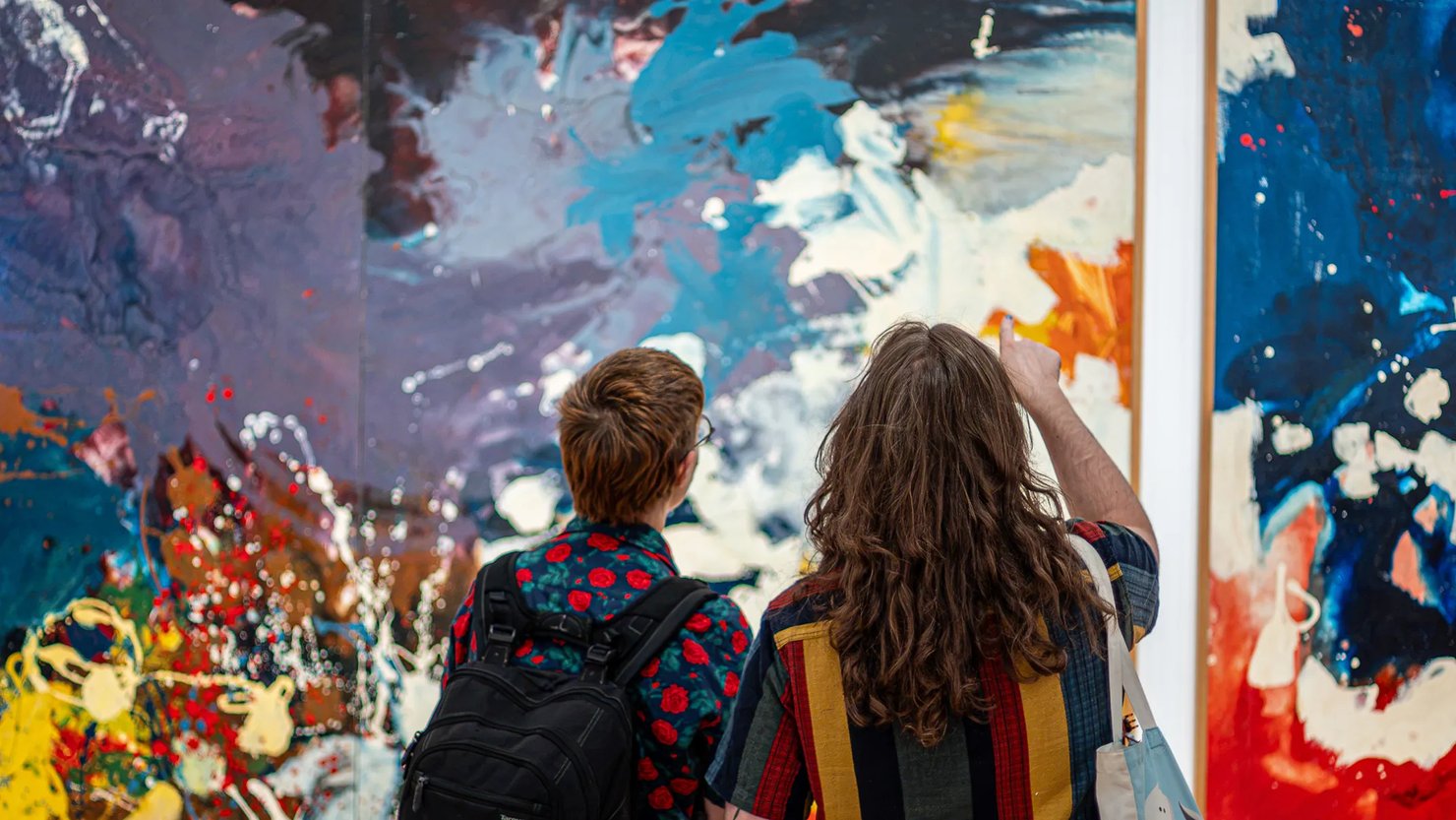 Photograph showing two people looking at large colourful abstract works