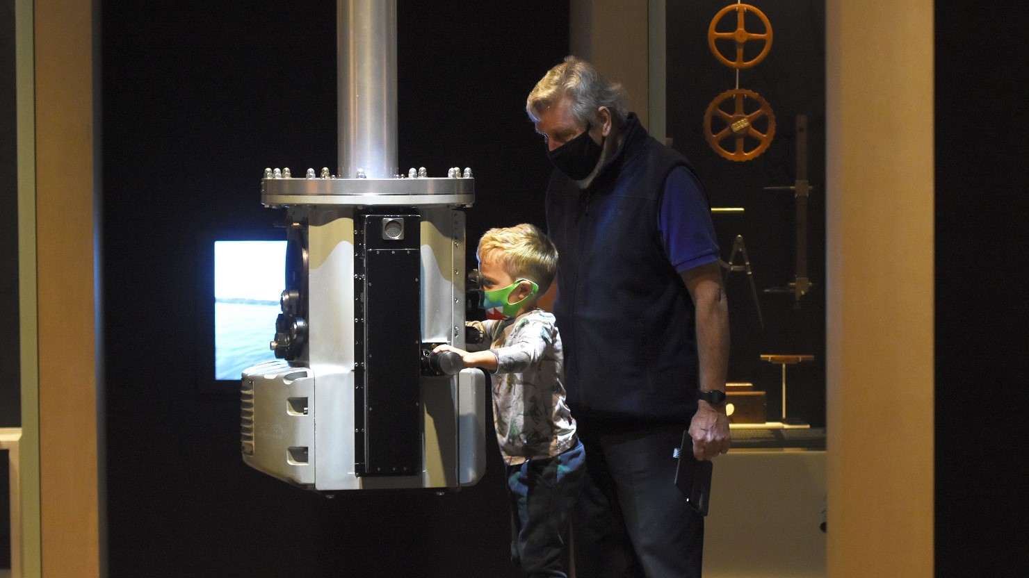 A boy and adult using one of the interactives in the Port of Plymouth gallery at The Box