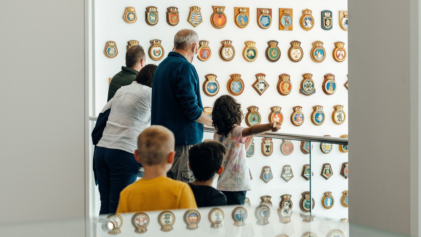 A family looking at the ship's badges at The Box, Plymouth