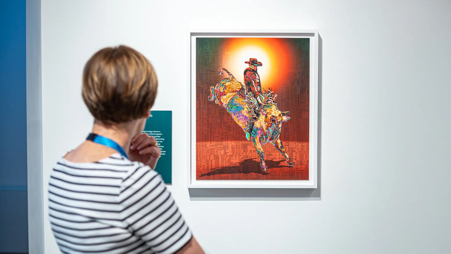 Photograph showing a woman looking at an artwork showing a cowboy on a horse