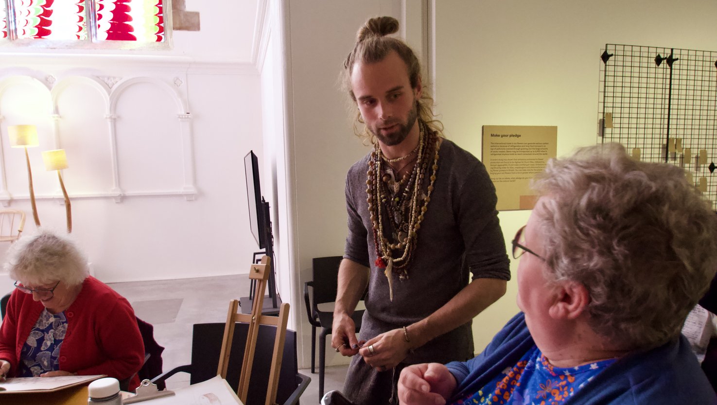 Artist Ralph Nel talks to two women during a drawing class