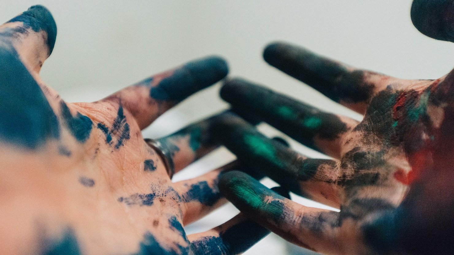 A pair of hands covered in different coloured paints