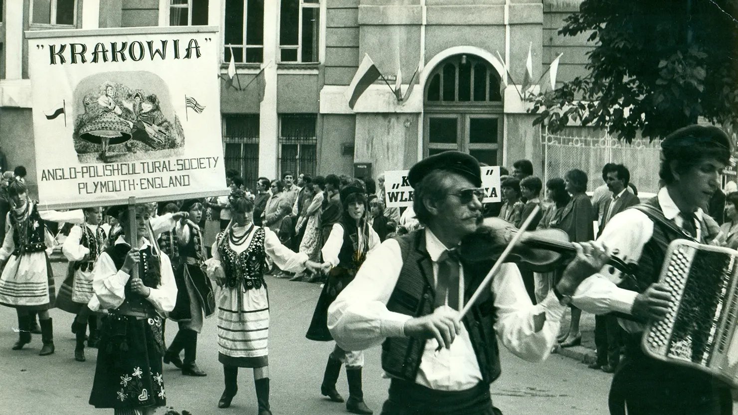 Black and white photograph showing a group of people in Polish costume on a parade.