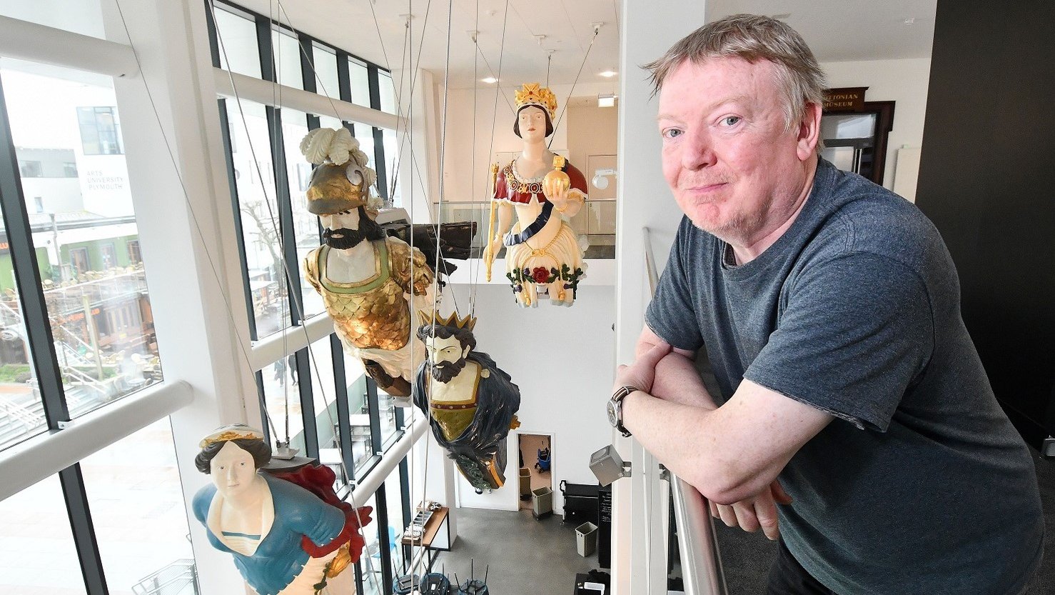 Artist Paul Rooney standing in the Active Archives gallery at The Box with the RN figureheads behind him