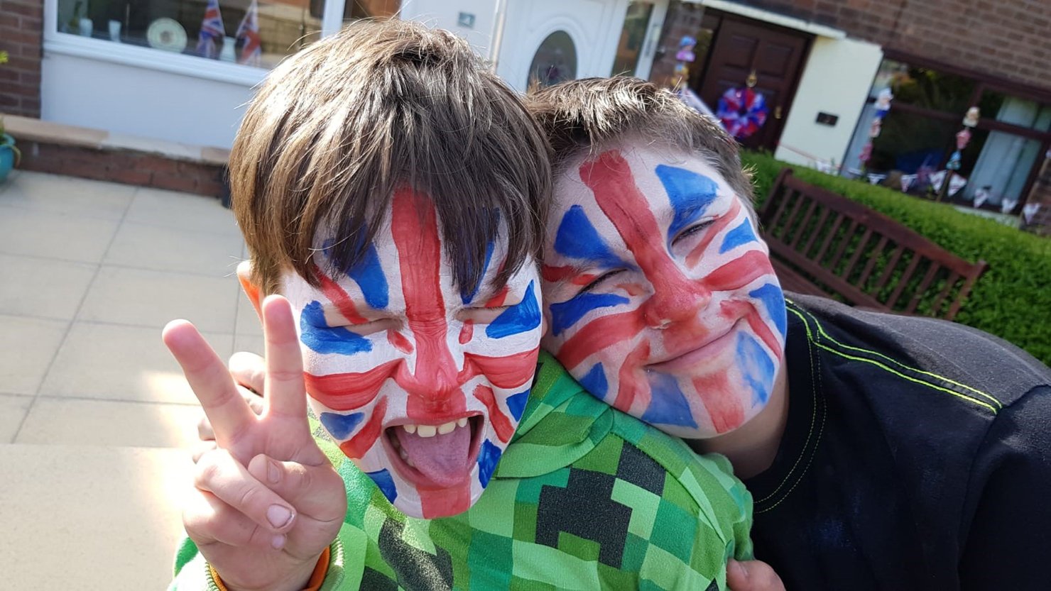 Two boys with their faces painted with the Union Jack flag
