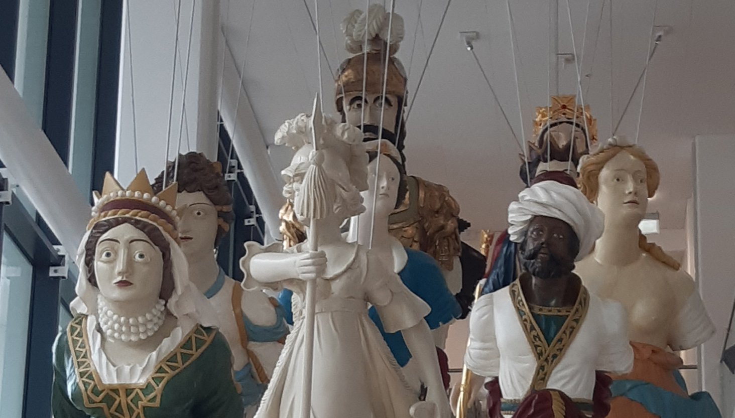 Group of historic ship's figureheads suspended from a ceiling