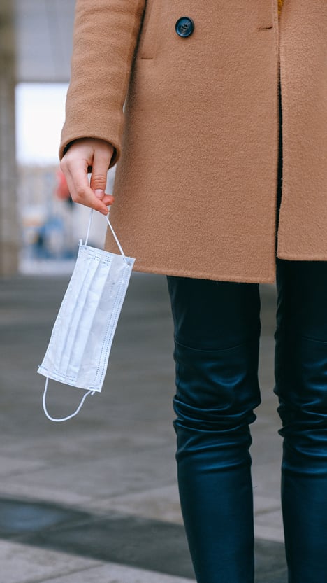 A woman holding a face mask in one hand