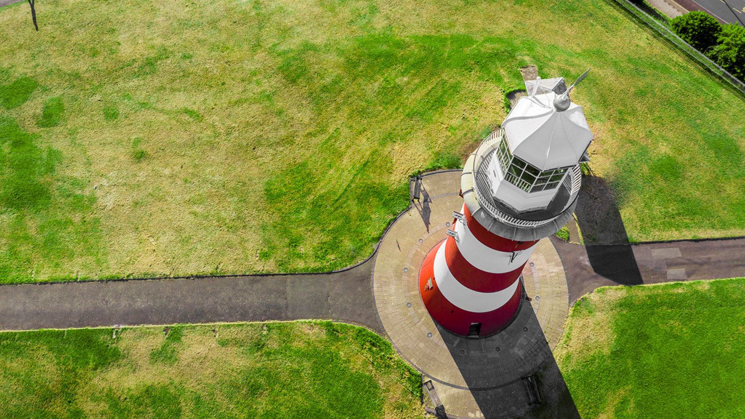 A drone image of Smeaton's Tower - a red and white striped lighthouse on Plymouth Hoe