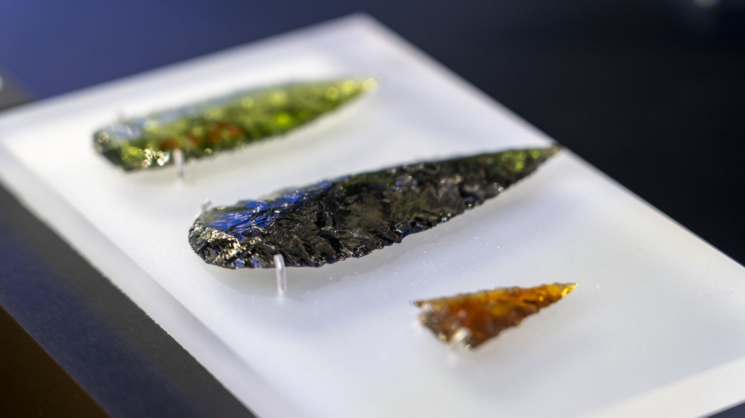 Three spearheads made from different coloured glass.