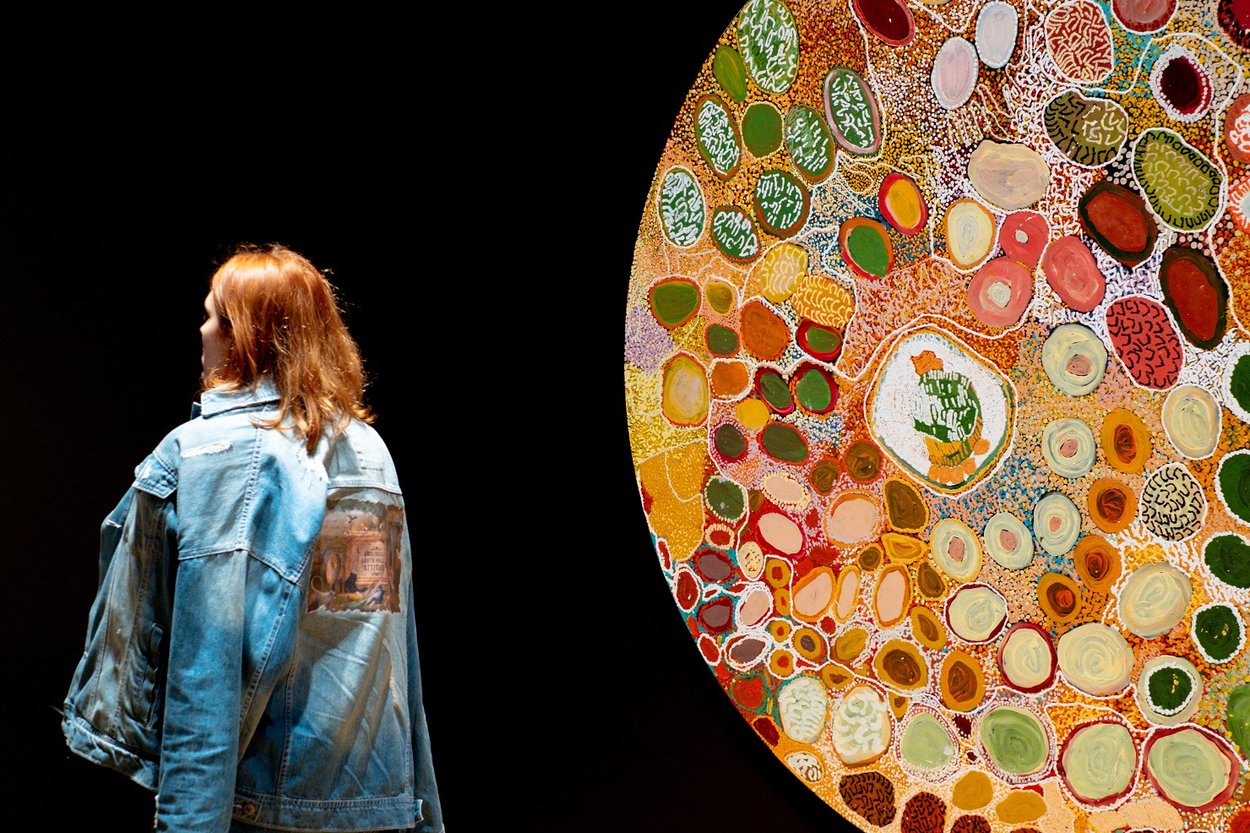 A female visitor looks at a large circular artwork on a wall. Image copyright Getty.
