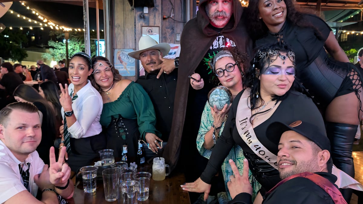 Birthday Wizards Night Out crew with hooded sorcerer, crystal ball, robes and house ties flash wands and peace signs