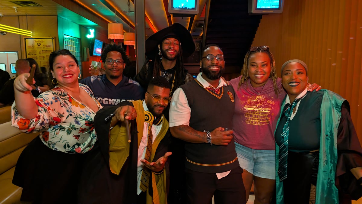 Hogwarts-house lineup in robes, a Hogwarts jersey, ties, and a pointed hat poses together at a Wizards Night Out sports-bar stop.