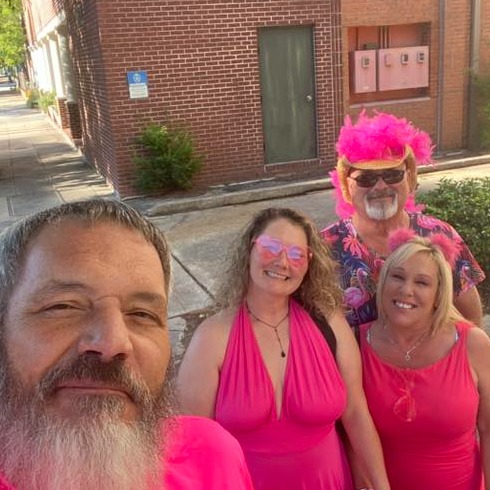 Sidewalk selfie of four crawlers in hot pink halter dresses and feathered hats