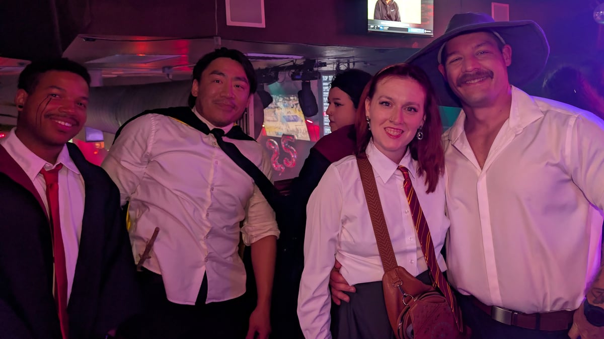Wizards Night Out crew in dress shirts and house ties grin together, one rocking a wide-brim wizard hat