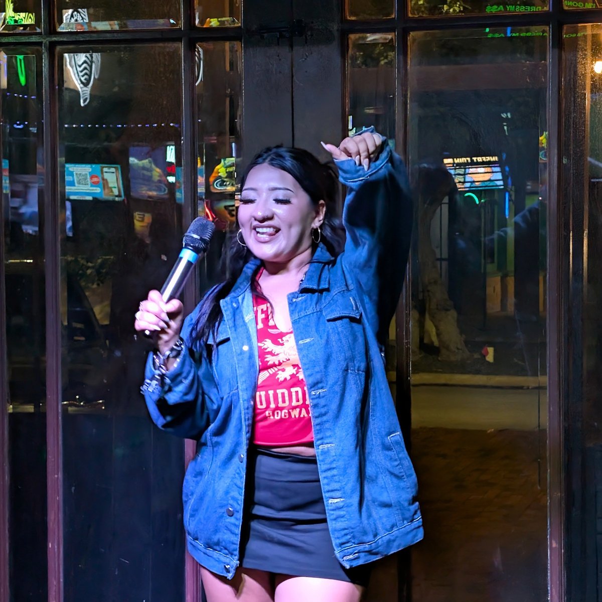 Witch in a Quidditch-Hogwarts tee belts a karaoke spell into the mic on the wizard crawl
