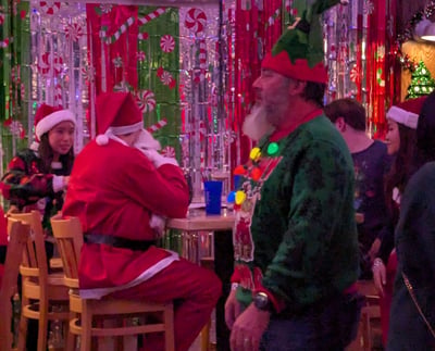 Santas and elves at a tinsel-covered bar