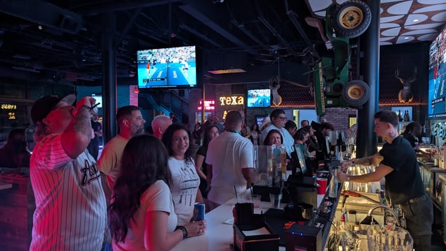 Bustling Texas sports bar packed with Wizards Night Out crawlers ordering potion-glass drinks at the long bar.