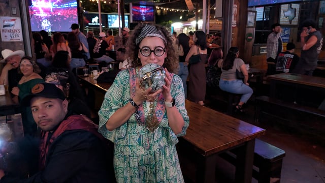 Birthday witch in round specs and headband cradles a crystal-ball potion glass at a Wizards Night Out stop