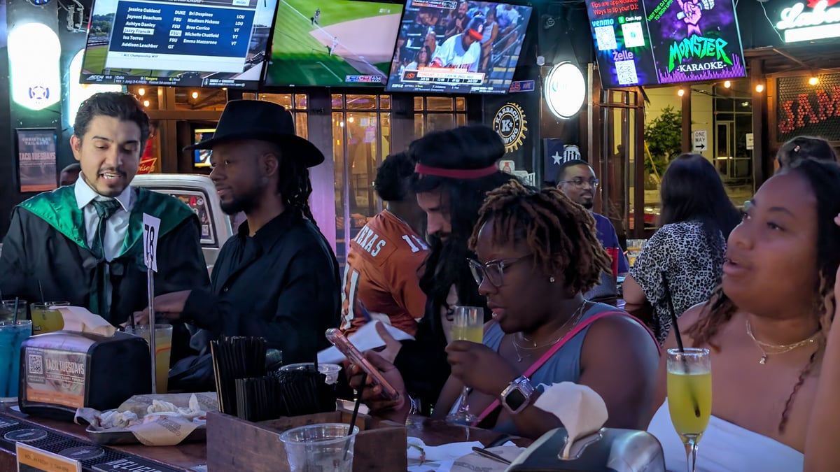 Robed bartender takes mimosa orders from a Wizards Night Out crew at a patio bar table