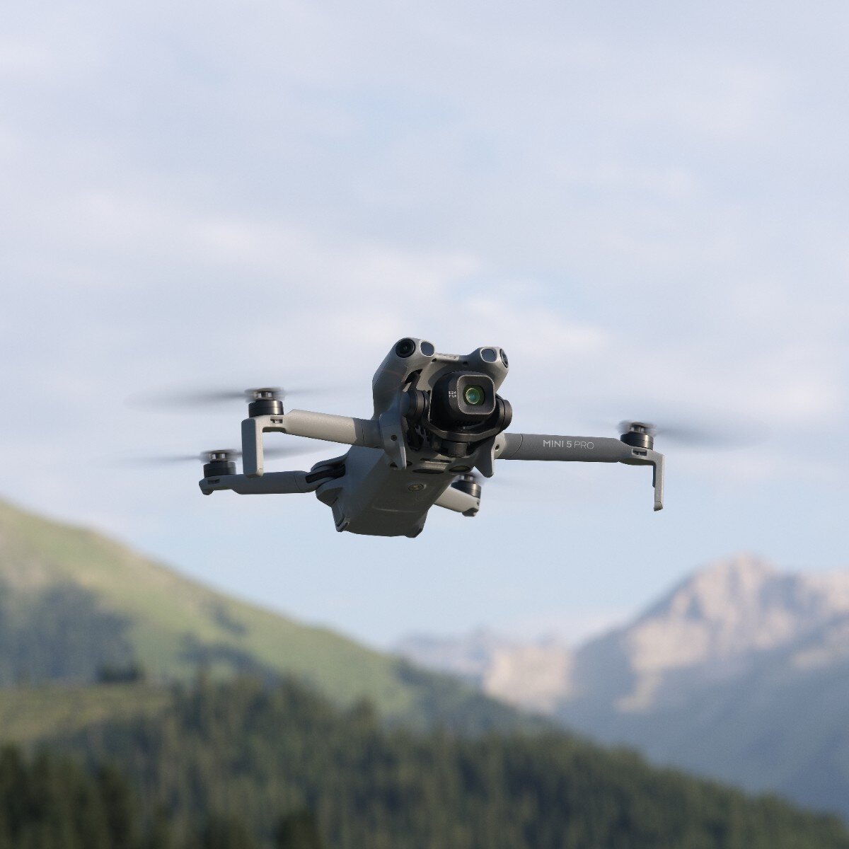 DJI Mini 5 Pro in flight in front of a mountain landscape