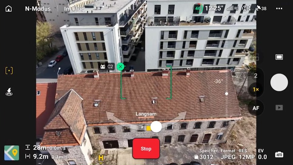 DJI Fly im Point-of-Interest-Modus: grüner Rahmen auf dem Dach, darunter der Regler mit der Anzeige „Langsam“.