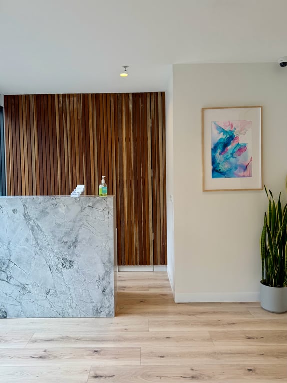 Reception at Aevum Clinic, with the timber wall and marble desk