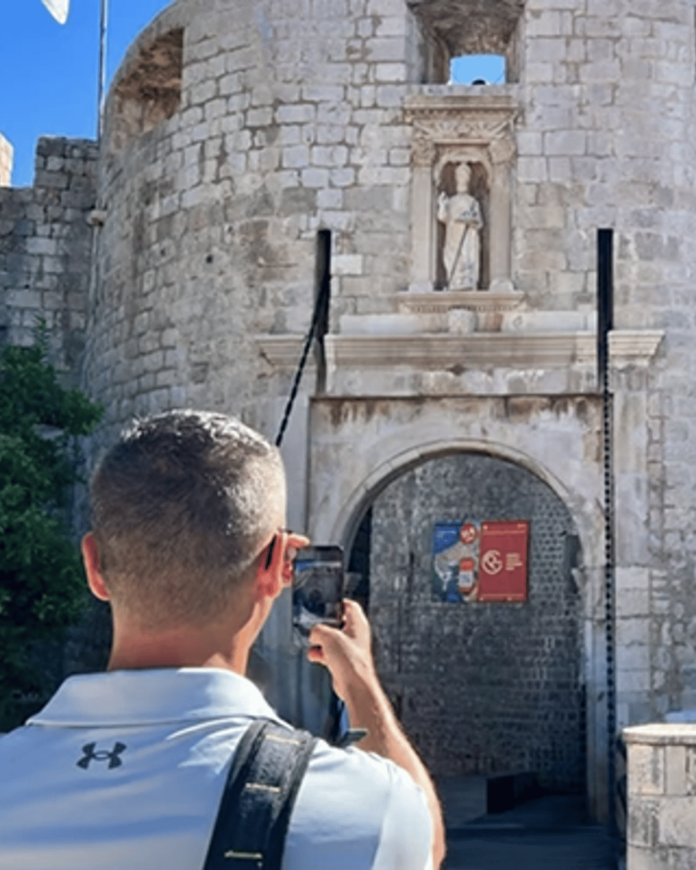 Dubrovnik ancient city walls overlooking Adriatic Sea, Tourists walking on medieval stone walls Dubrovnik, Panoramic view of Old Town from city walls, Walking tour group exploring Dubrovnik ramparts, Stunning Adriatic coastline view from Dubrovnik walls