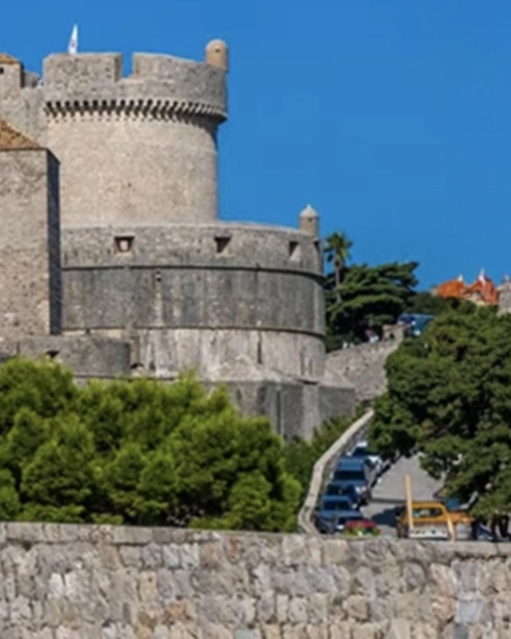 Dubrovnik ancient city walls overlooking Adriatic Sea, Tourists walking on medieval stone walls Dubrovnik, Panoramic view of Old Town from city walls, Walking tour group exploring Dubrovnik ramparts, Stunning Adriatic coastline view from Dubrovnik walls
