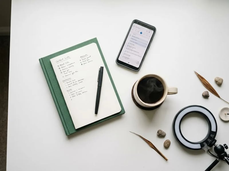 Notebook, phone and ring light laid out for content planning