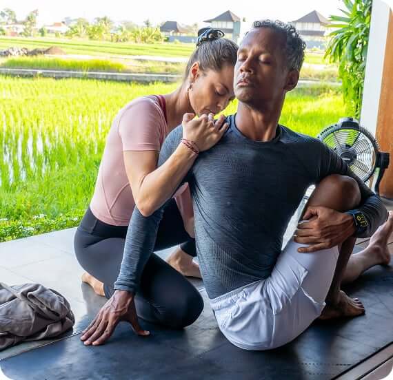Yann Cadic giving a hands-on adjustment to a student in seated twist at the Loka shala, Bali