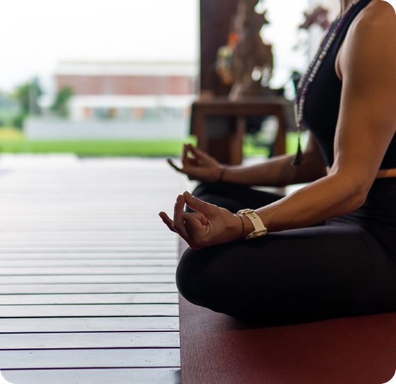 Close-up of a hand in chin mudra during seated meditation on a wooden deck