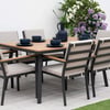 Stylish outdoor dining table set with six cushioned chairs, a wooden tabletop, and decorative blue dishware, perfect for garden or patio entertaining.
