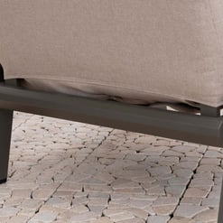 Modern outdoor patio chair with cushioned seat and sturdy metal frame on stone paver flooring for stylish garden or backyard furniture.